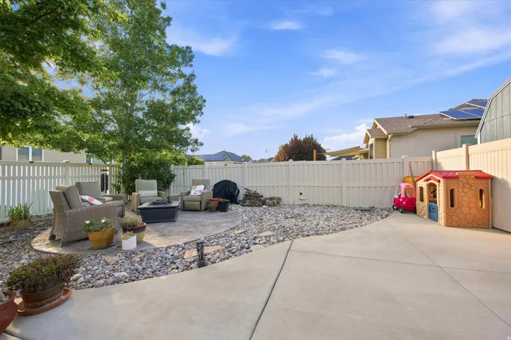 Expansive concrete patio with a circular paver seating area, surrounded by decorative rock landscaping