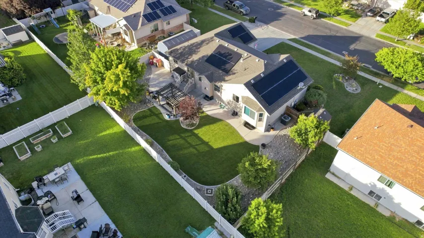 Expansive backyard with a manicured lawn, established landscaping, and a pergola-covered patio
