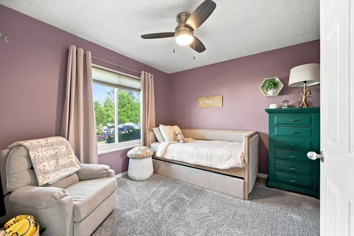 Ceiling fan with integrated lighting, large window with blinds, soft purple wall color, built-in shelving, paneled door