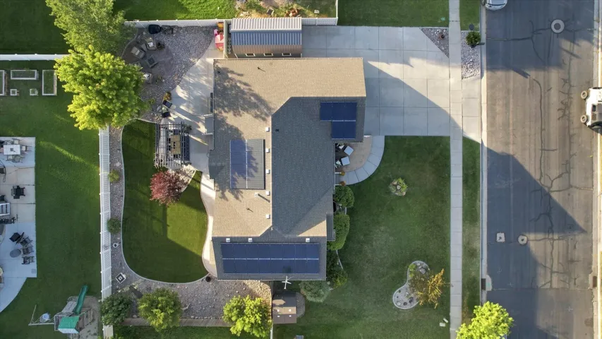 Multiple solar panel arrays, expansive green lawn, concrete driveway, concrete patio, and a privacy fence