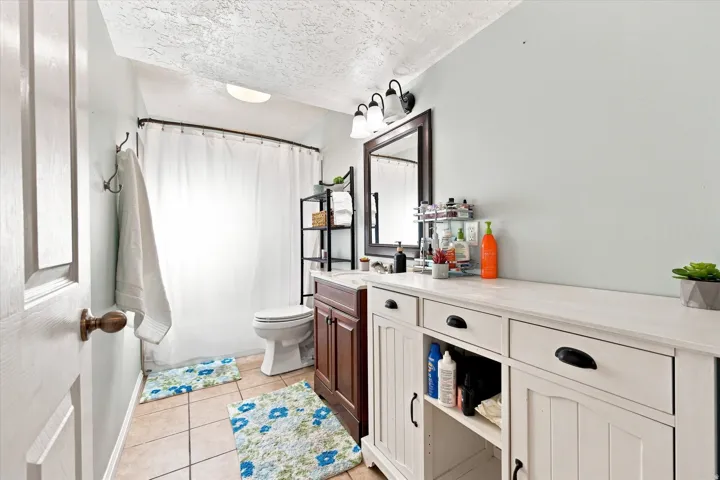 Wood-finish vanity with countertop, framed wall mirror, and tiled flooring