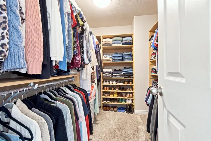 Walk-in closet featuring carpet flooring, built-in shelving, and multiple hanging rods
