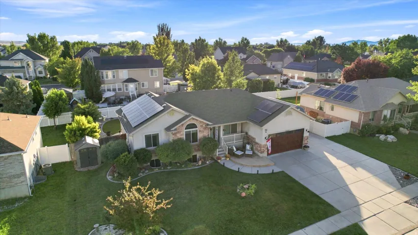 Single-story residence featuring a two-car garage, solar panels, and a concrete driveway