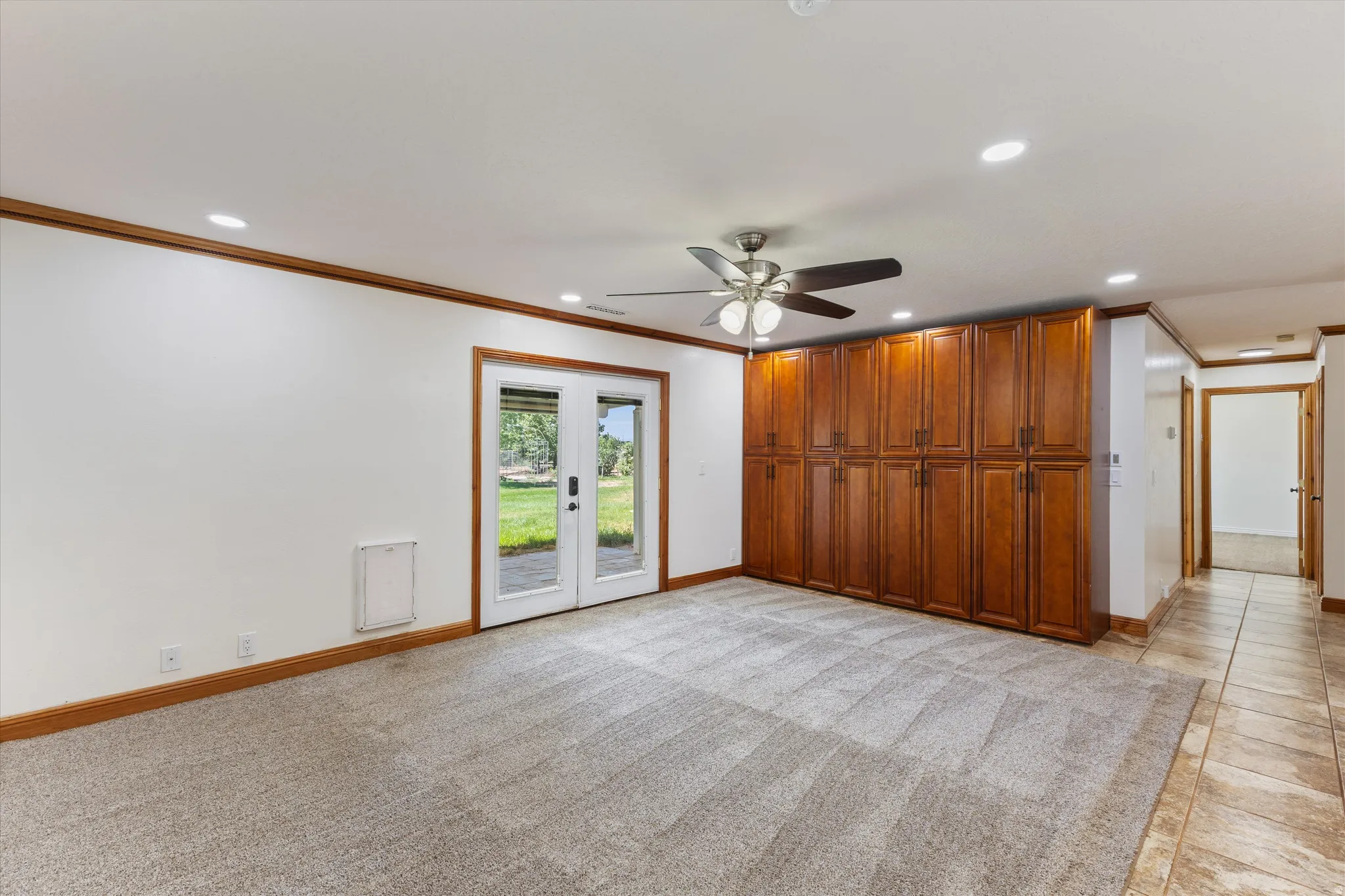 Recessed lighting, wood-finish trim, ceiling fan, double French doors, and extensive built-in cabinetry