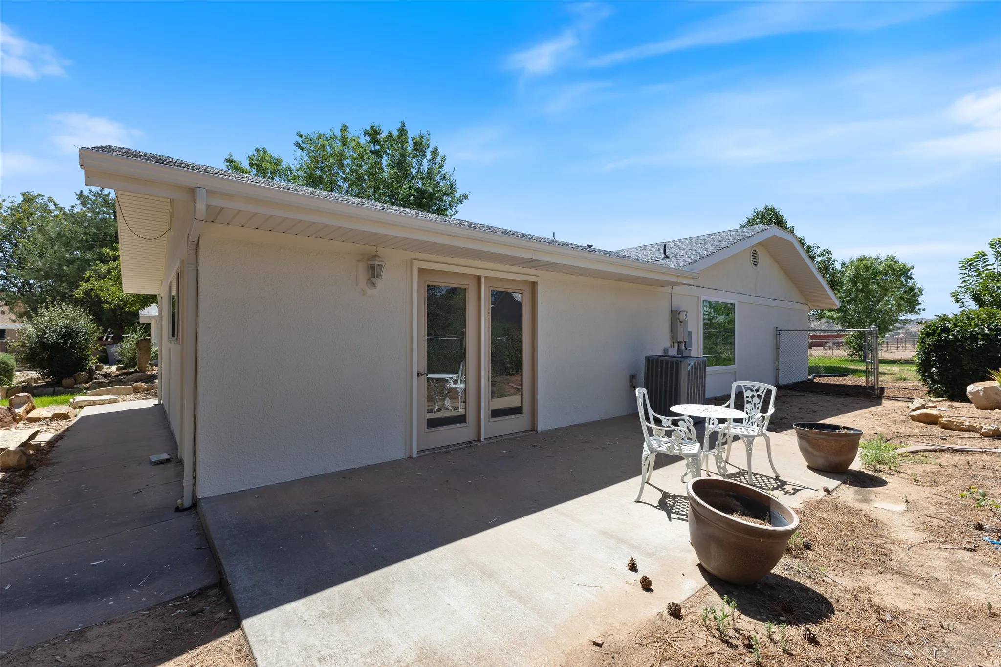 Exterior patio with double French doors, a window, and stucco siding
