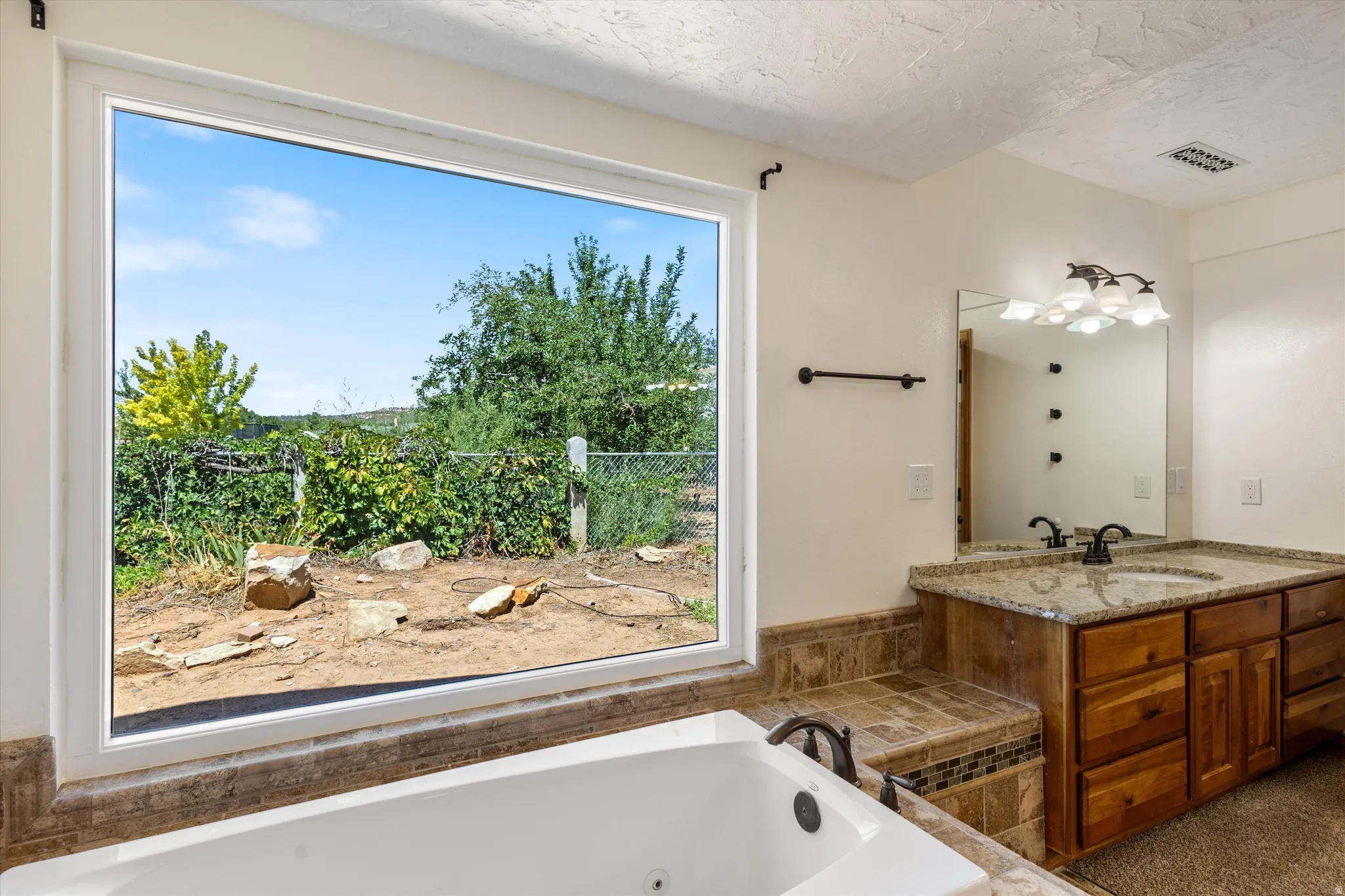 Double vanity with undermount sinks, stone countertop, and wood-finish cabinetry