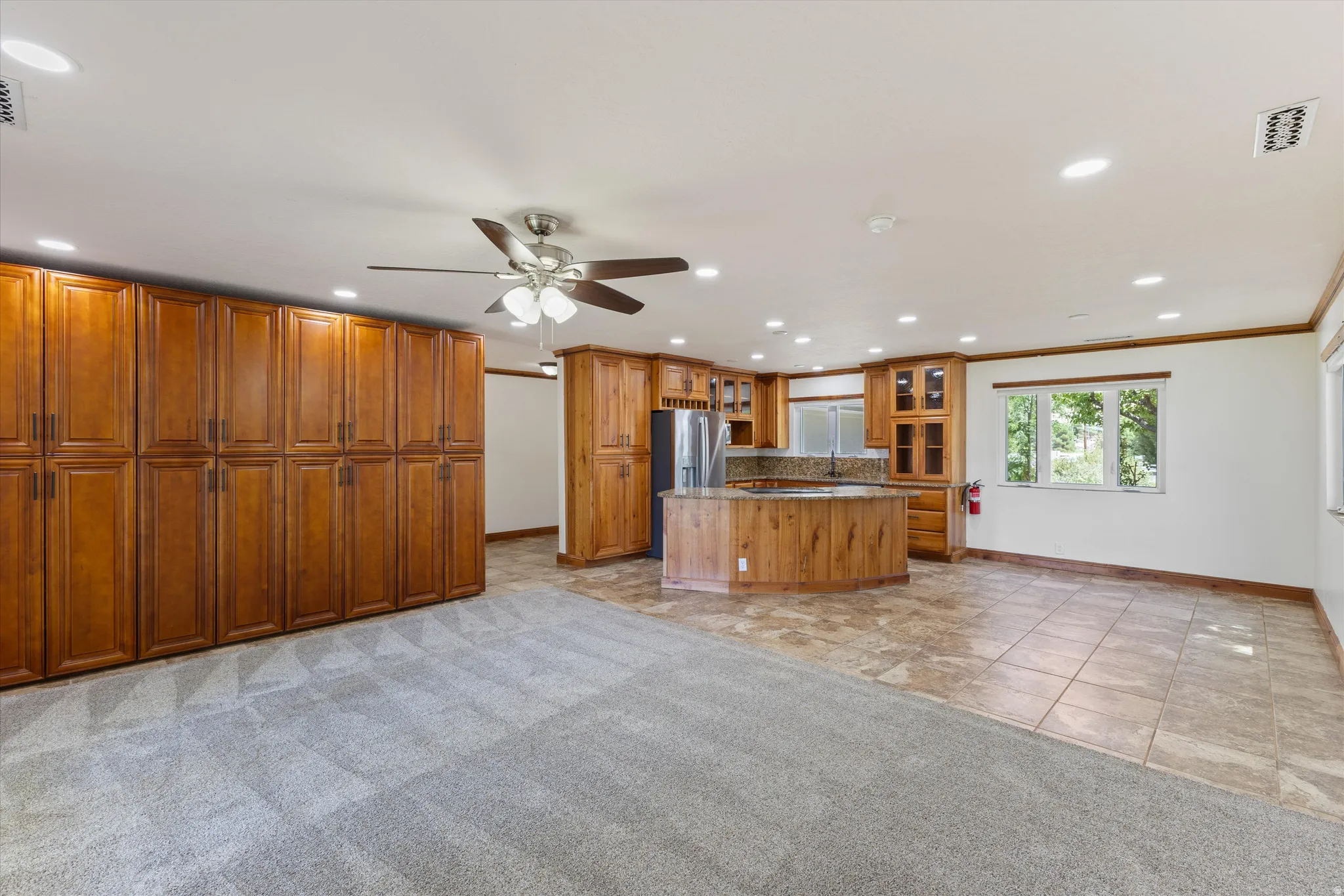 Expansive room featuring extensive wood cabinetry, recessed lighting, ceiling fan, and mixed flooring with carpet and tile