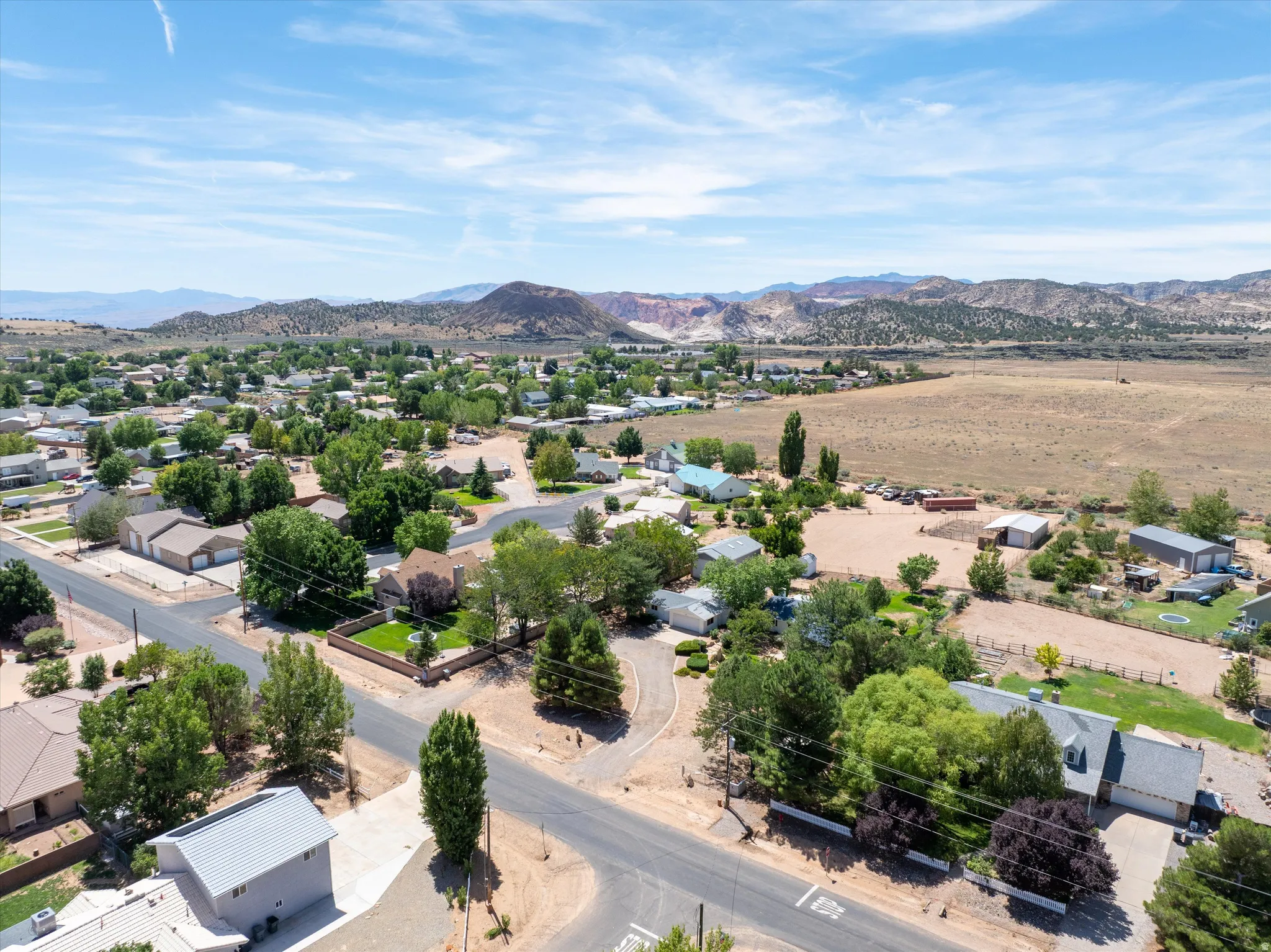 Aerial perspective showcasing residential properties, mature trees, and mountainous terrain