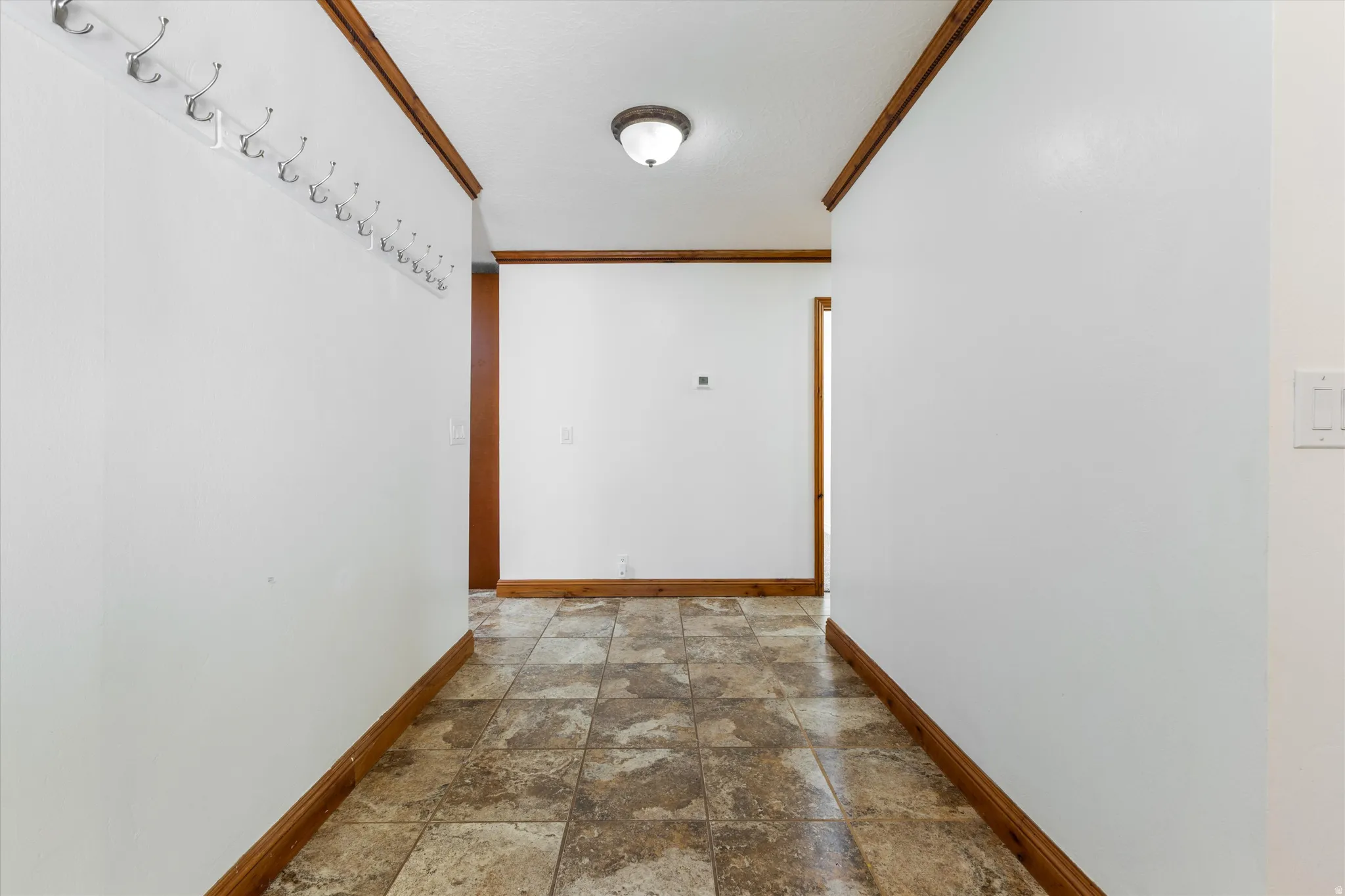 Hallway featuring tiled flooring, white walls, and wood trim