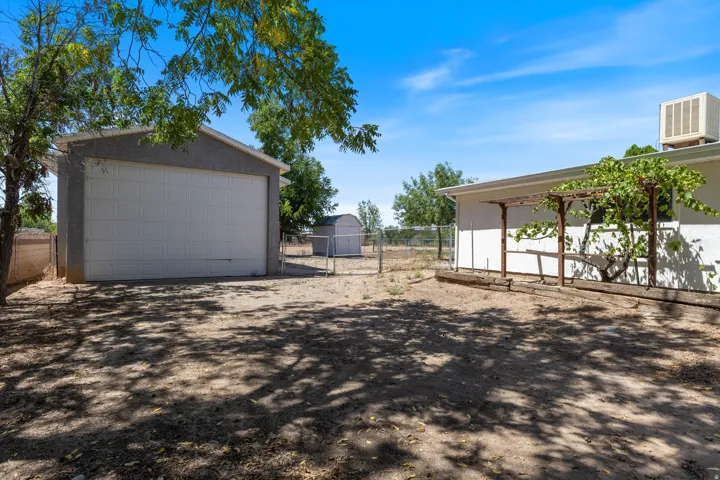 Detached garage featuring an overhead door, adjacent to a storage shed and fenced perimeter