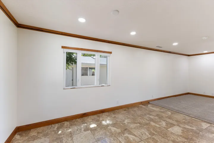 Recessed lighting, wood trim, white walls, and a window with a white frame