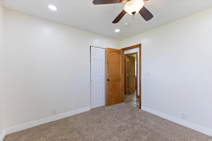 Carpeted flooring, recessed lighting, ceiling fan with integrated light, wood-finish interior door, and a bi-fold closet door