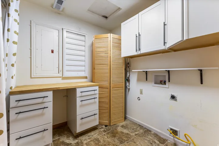 White cabinetry with black hardware, wood-finish countertop, and wall-mounted shelving