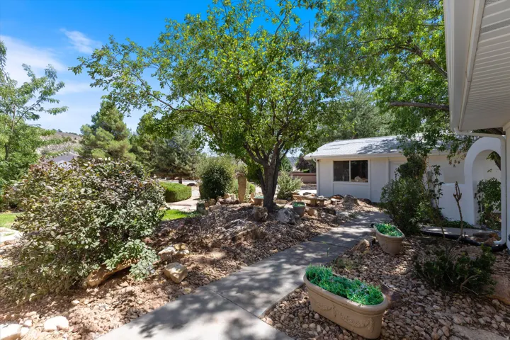 Paved pathway with mature trees, established landscaping, and a white stucco exterior building