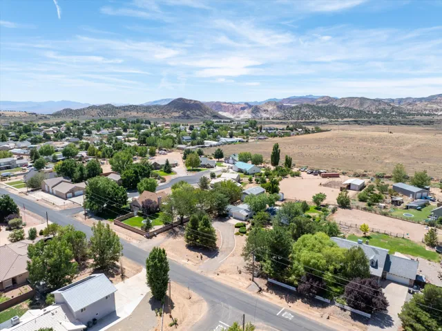 Aerial perspective showcasing residential properties, mature trees, and mountainous terrain