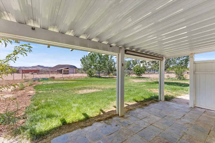 Covered patio featuring an expansive grass area, privacy fencing, and distant mountain terrain