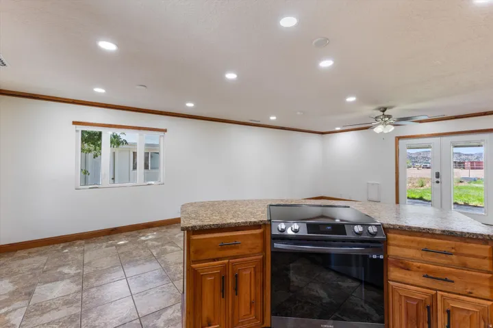 Kitchen island with a built-in range, wood cabinetry, and speckled countertops