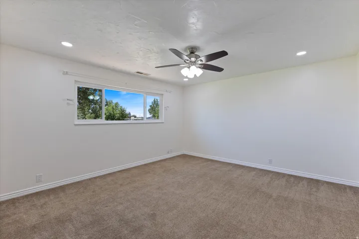 Carpeted flooring, recessed lighting, ceiling fan, and large window