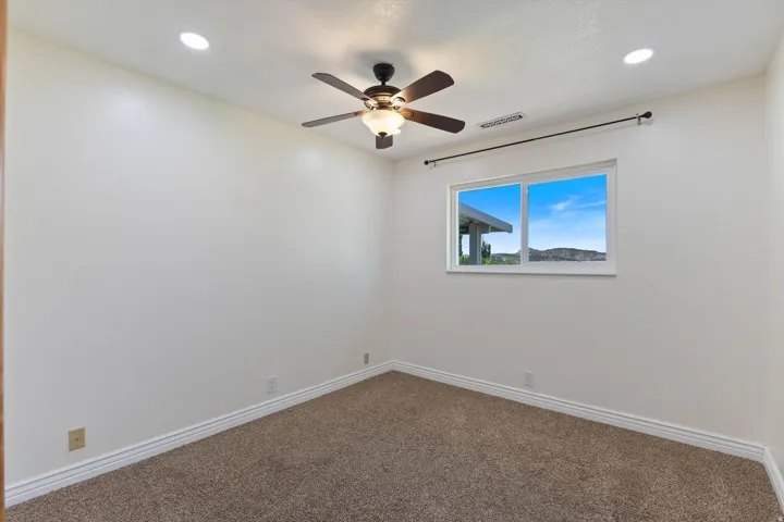 Recessed lighting, ceiling fan with light fixture, window with mountain scenery, and carpet flooring