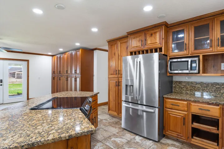 Kitchen featuring abundant wood cabinetry, integrated stainless steel appliances, granite countertops, and recessed lighting