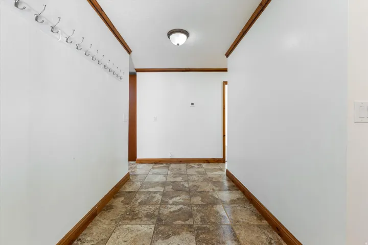 Hallway featuring tiled flooring, white walls, and wood trim