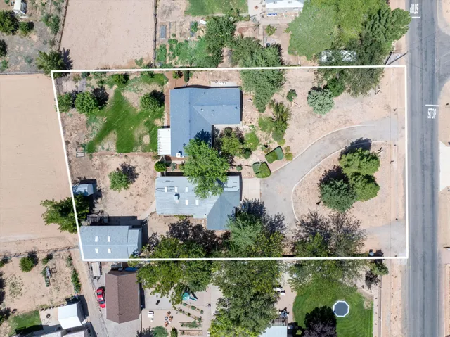 Expansive property featuring two structures, mature trees, a curved driveway, and a partially grassed area