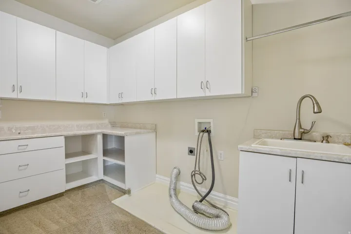 Extensive white cabinetry, integrated sink with gooseneck faucet, light-toned countertop, and open shelving