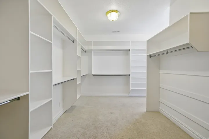 Custom closet system featuring extensive shelving, multiple hanging rods, built-in dresser style storage, and recessed lighting