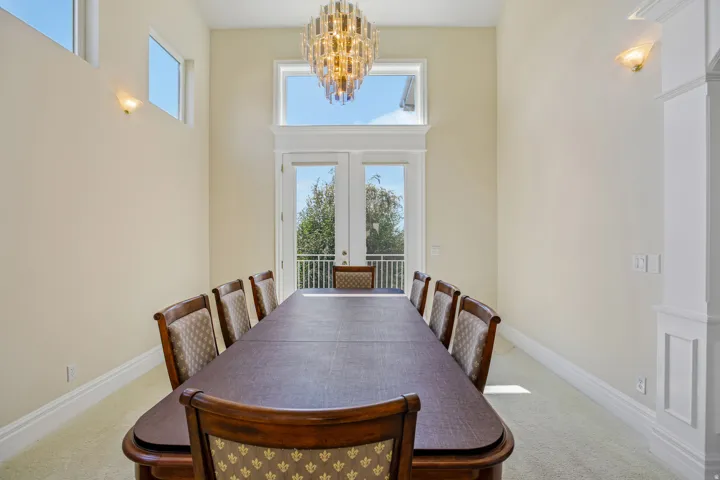 Dual French doors, transom windows, and an ornate chandelier illuminate the space