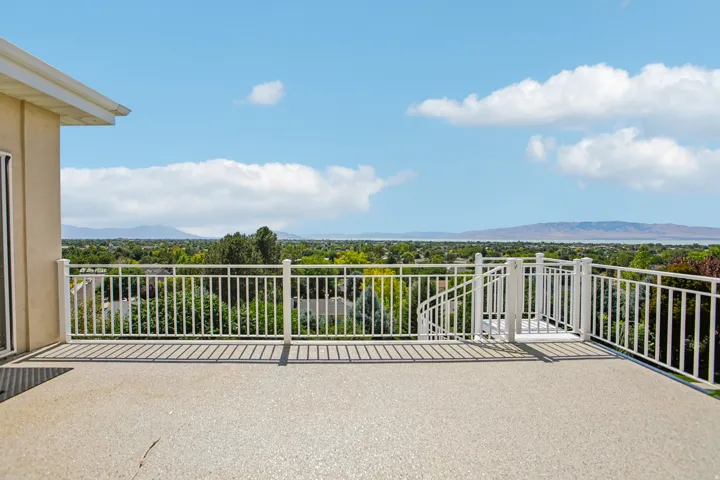 Expansive balcony featuring a textured concrete surface, white metal railings, and a built-in spiral staircase
