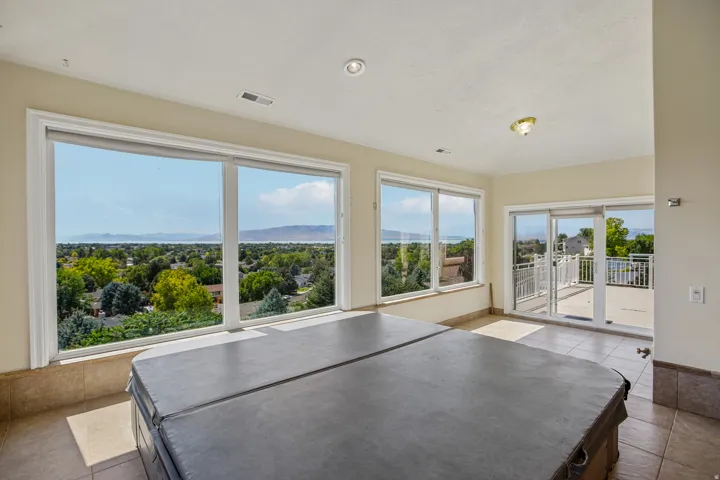Expansive windows, tiled flooring, recessed lighting, and sliding glass doors leading to an outdoor deck