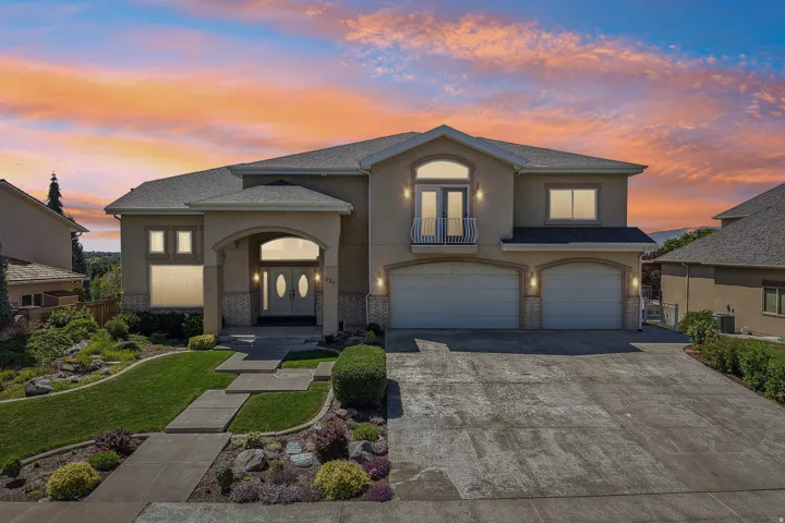 Stucco exterior with stone accents, arched entry, two-car garage, and a second-story balcony