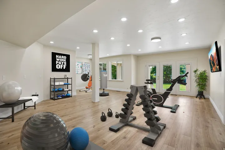 Expansive room featuring wood-finish flooring, recessed lighting, double French doors, and multiple windows