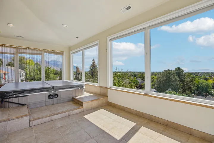 Indoor spa tub with tiled surround, large windows, and recessed lighting
