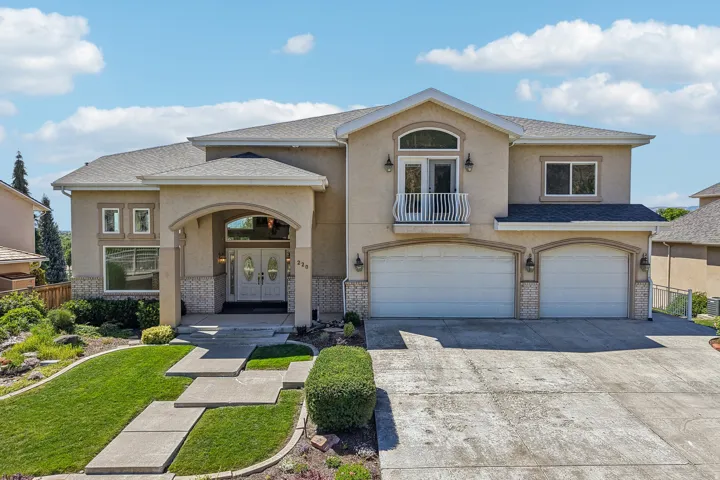 Stucco exterior with a balcony, arched entry, double front doors, and a two-car garage