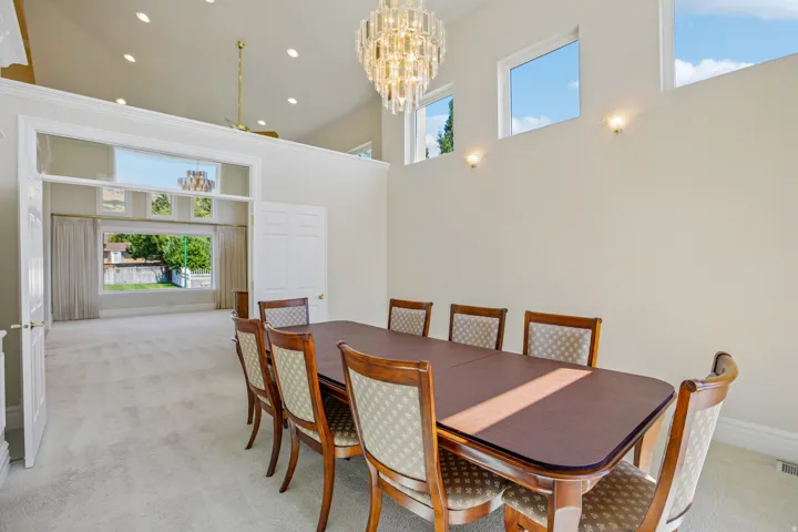 Vaulted ceiling with an ornate chandelier, multiple transom windows, recessed lighting, and an expansive doorway