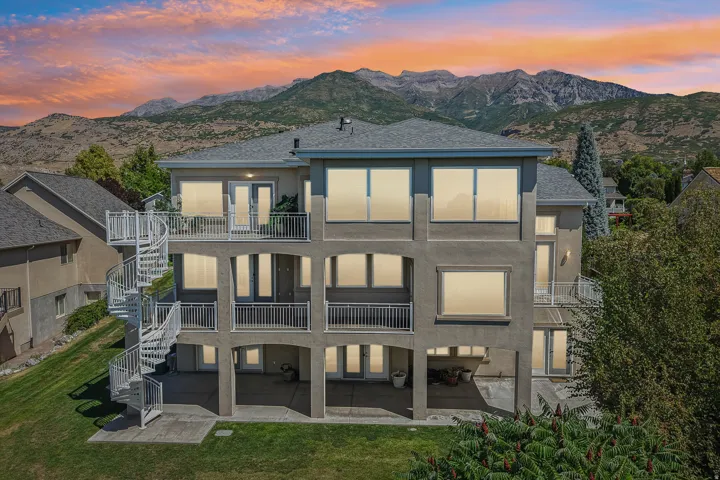 Multi-level exterior with stucco finish, multiple balconies, a spiral staircase, and a mountain backdrop