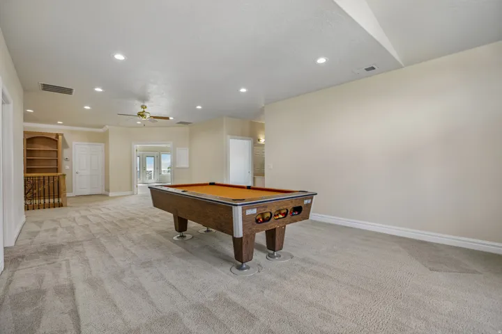 Expansive carpeted room with recessed lighting and a ceiling fan