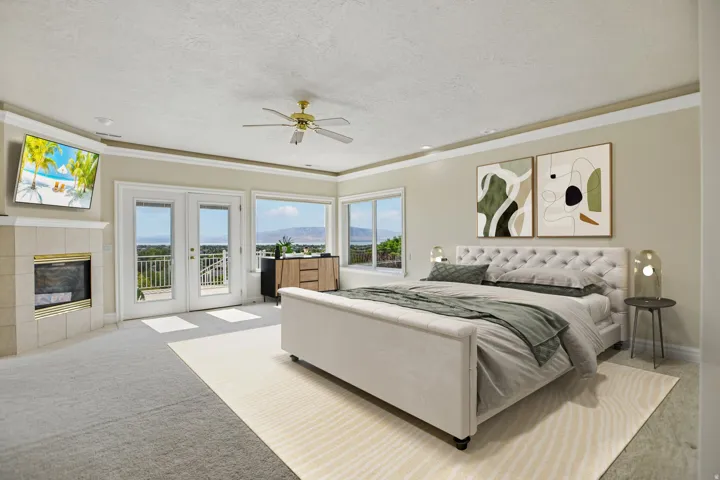 Wall-mounted television, fireplace with tile surround, double glass doors with transom windows, multiple windows, and a ceiling fan