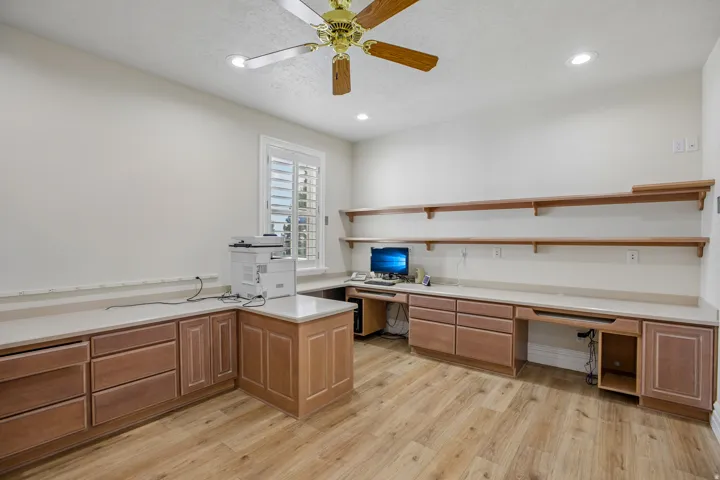 Built-in wood cabinetry with light-toned countertops, wood-finish flooring, recessed lighting, and a ceiling fan