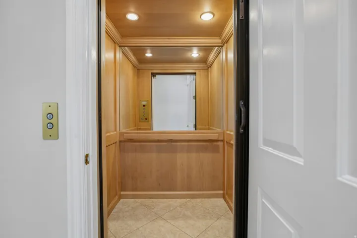 In-home elevator featuring wood paneling, recessed lighting, and tile flooring
