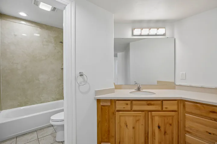 Wood-finish vanity with a light-toned countertop, integrated sink, and chrome faucet