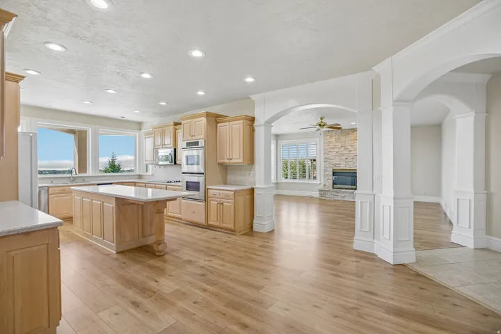 Light wood-finish flooring, recessed lighting, and white arched columns