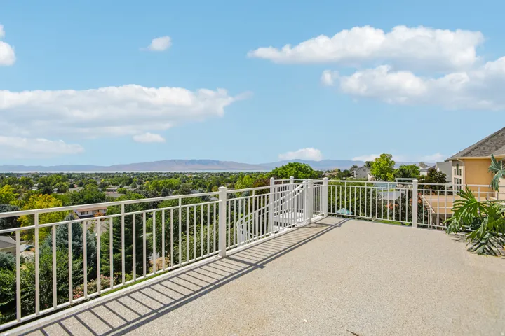 Expansive outdoor terrace featuring a textured concrete surface, white metal railings, and broad scenery