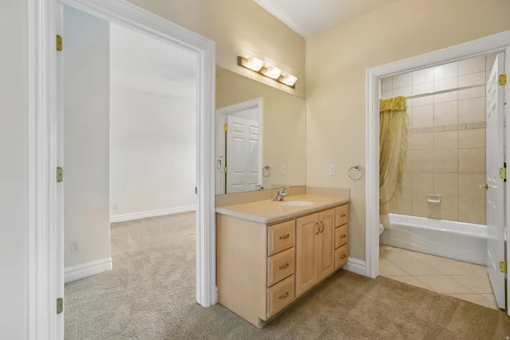 Bathroom vanity with a single sink, light wood-finish cabinetry, and a full-width mirror