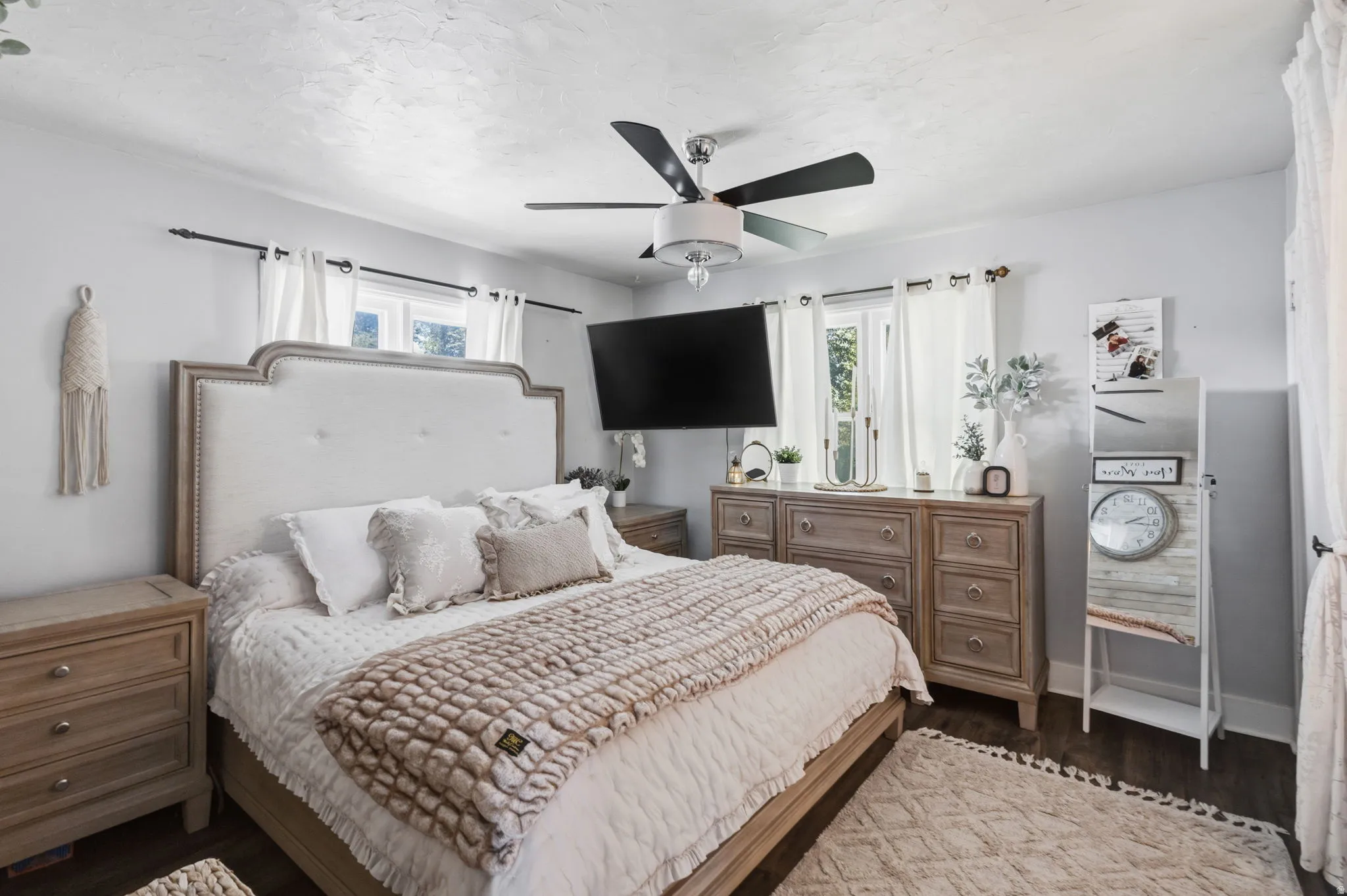 Ceiling fan with integrated lighting, wood-finish flooring, multiple windows, and light-toned wall finishes