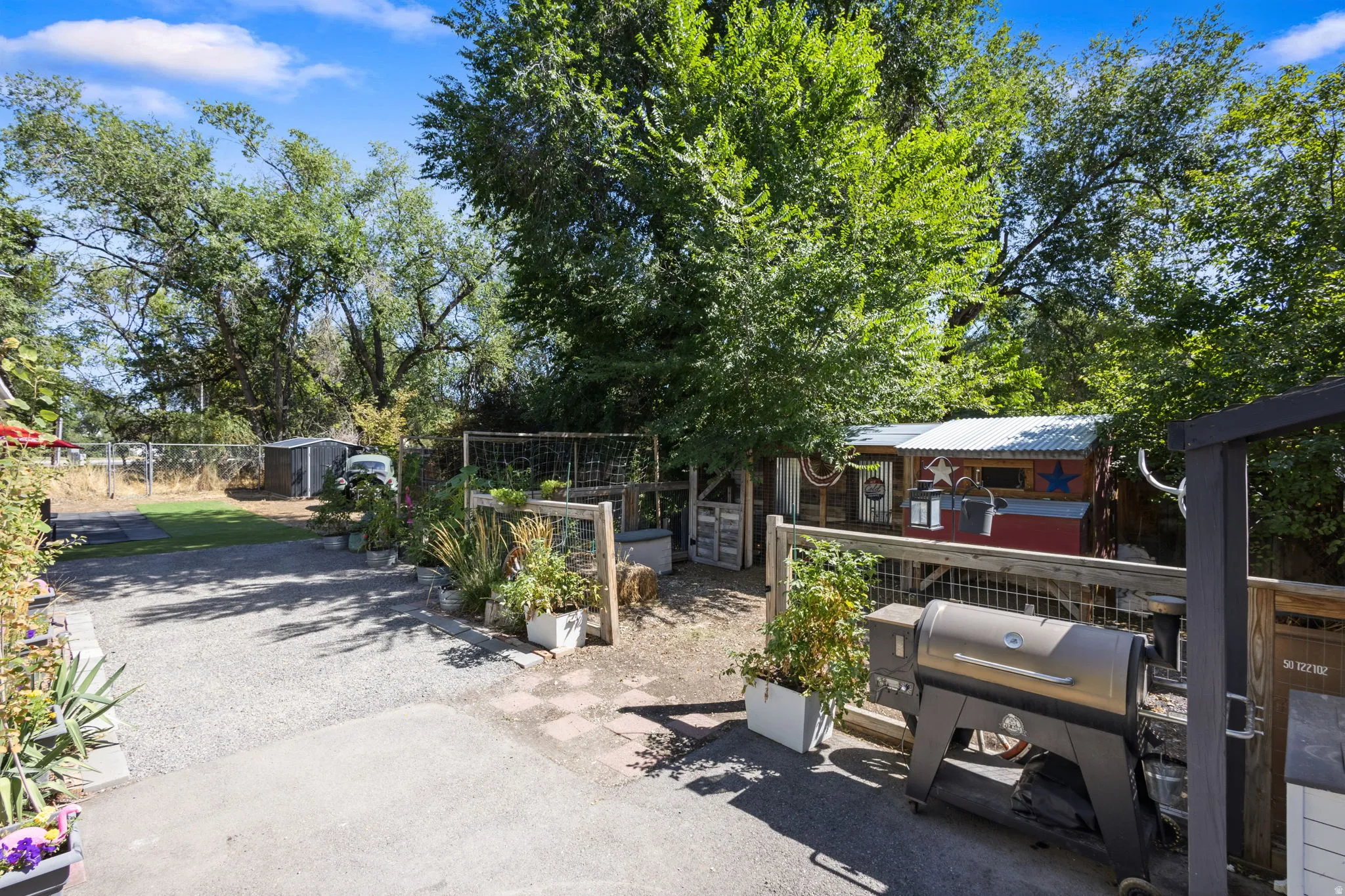 Expansive outdoor space featuring a graveled area, paved sections, and a wood-fenced enclosure