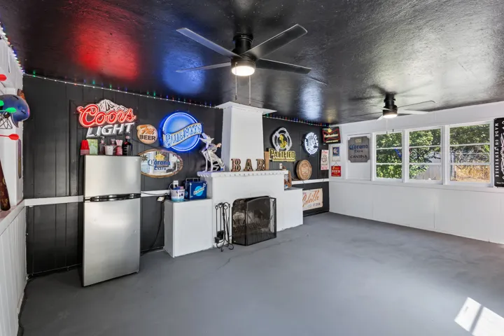 The "PARTY SHED" . A separate structure on the property for entertaining. Painted concrete flooring, white wainscoting, multiple windows, and ceiling fans