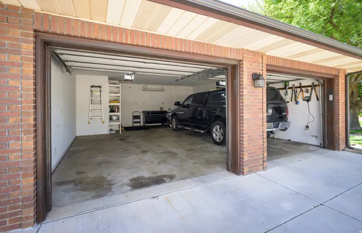 Brick exterior garage with multiple bays, concrete flooring, and overhead lighting