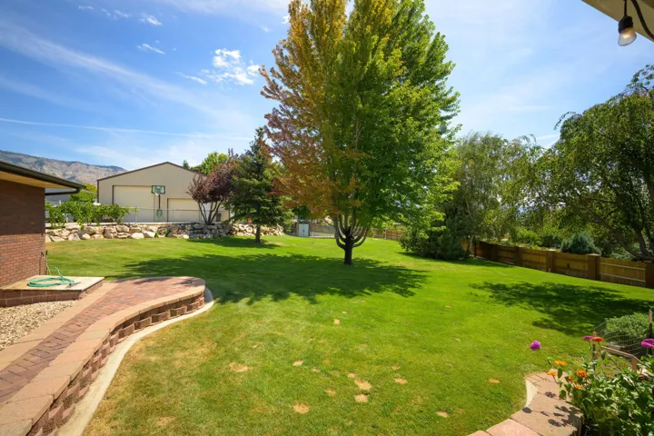 Expansive green lawn with mature trees and a brick retaining wall
